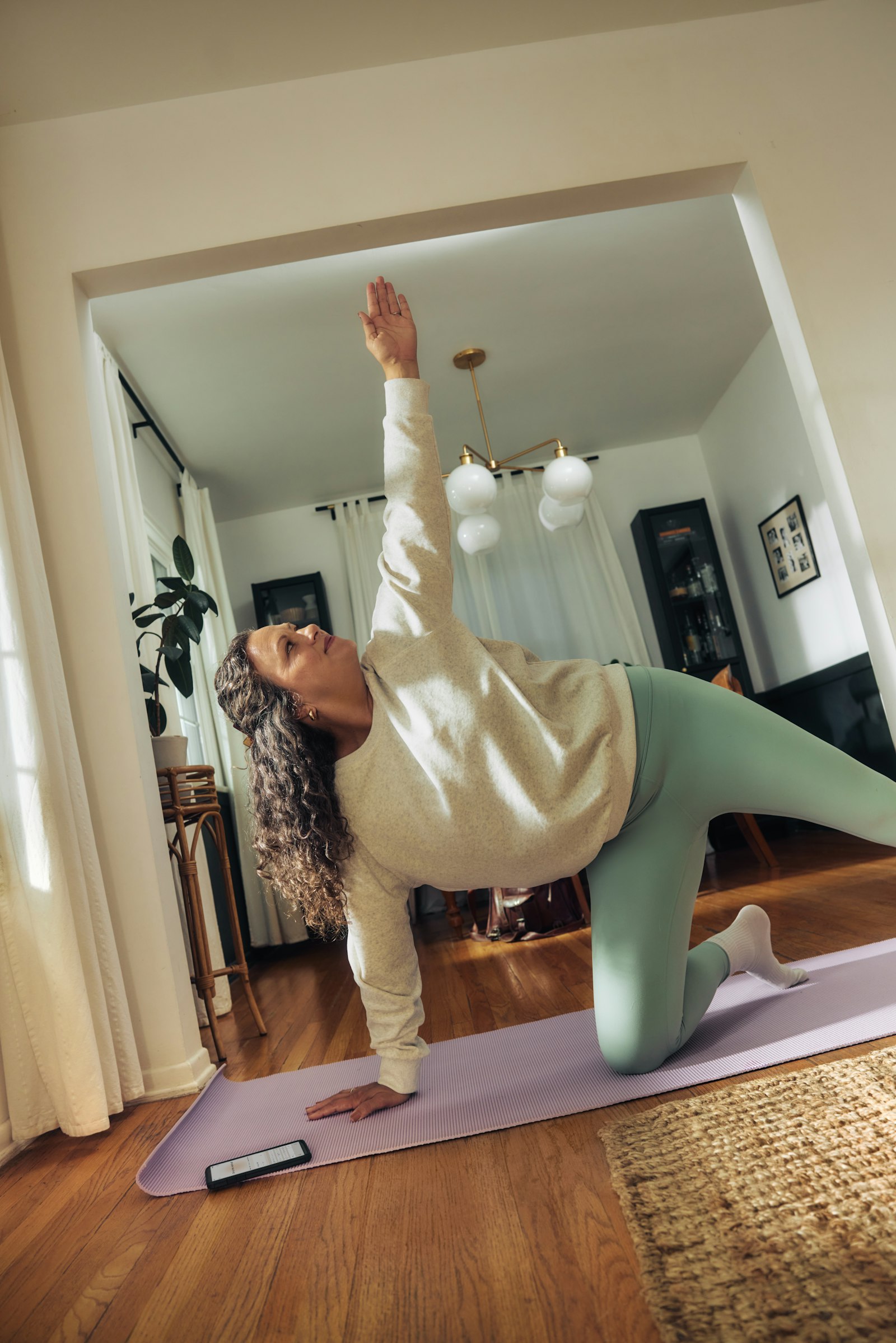 A woman doing a yoga pose on a mat at home